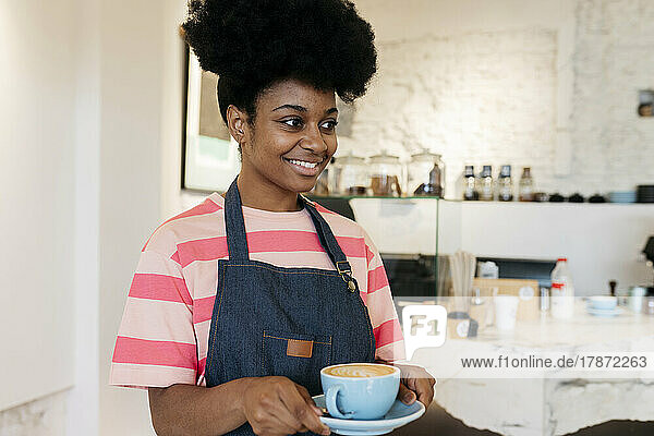 Smiling woman with Afro hairstyle holding coffee cup