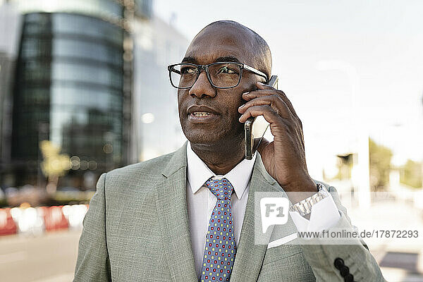 Mature businessman talking on smart phone at financial district