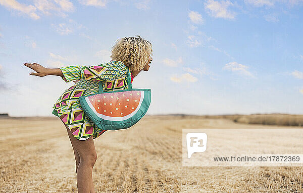 Young woman with watermelon shape bag enjoying at field
