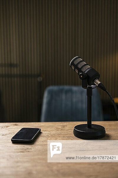 Mobile phone by microphone on desk in recording studio
