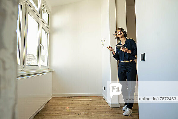 Smiling real estate agent with tablet PC standing at doorway