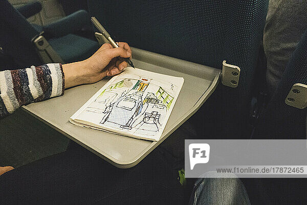 Hand of girl drawing in train
