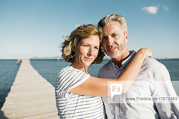 Smiling mature woman and man standing on jetty