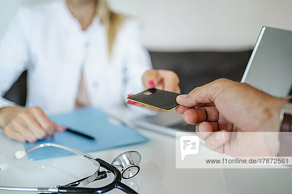 Patient handing over card to doctor in medical practice