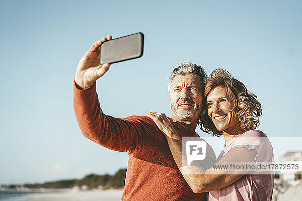 Smiling man taking selfie with woman through smart phone