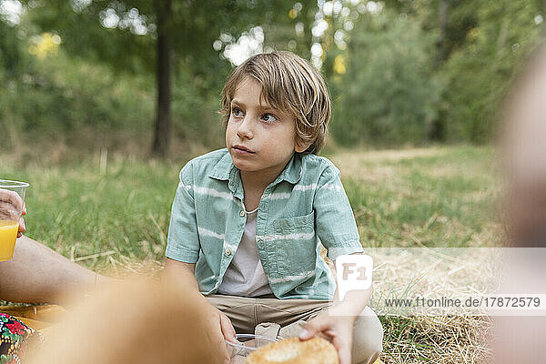 Boy holding bread sitting at park