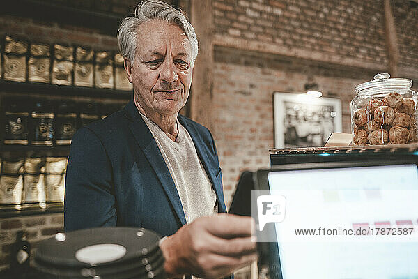 Senior businessman paying through smart phone at cafe counter
