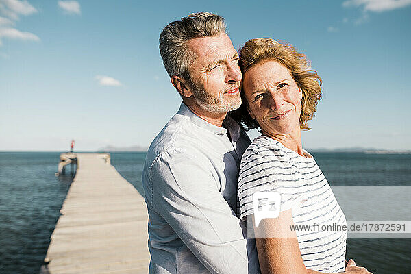 Lächelndes älteres Paar  das an einem sonnigen Tag Zeit miteinander am Steg verbringt