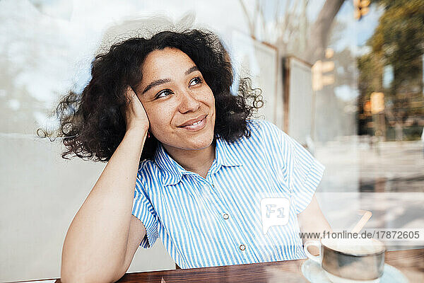 Smiling woman with coffee cup sitting at table in cafe
