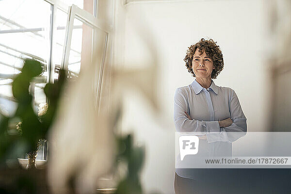 Confident businesswoman standing with arms crossed in office