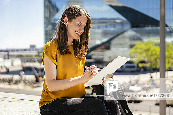 Smiling businesswoman using digitized pen on tablet PC