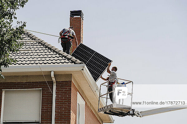Technicians installing solar panels on rooftop