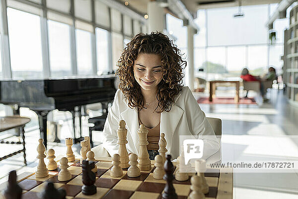 Smiling young businesswoman playing chess in office