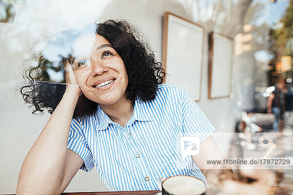 Happy woman with coffee cup sitting at table in cafe