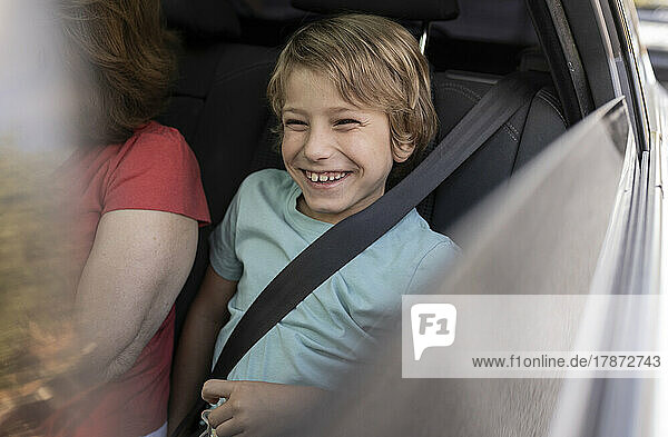 Smiling boy sitting by grandmother in car
