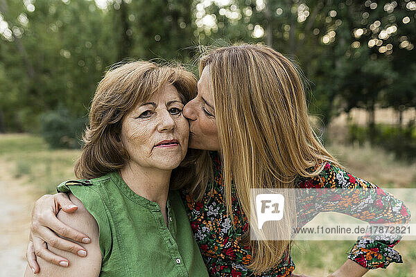 Loving daughter kissing mother at park