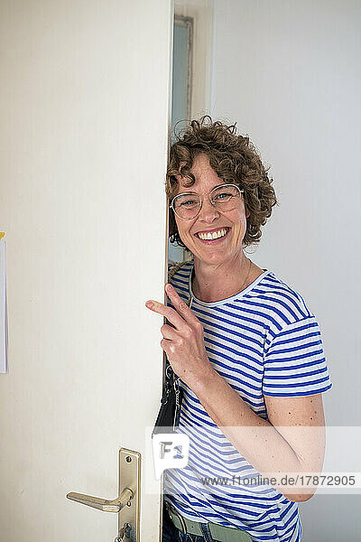 Happy woman wearing eyeglasses standing with house key by door