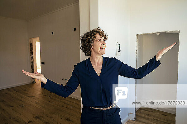 Happy real estate agent standing with arms outstretched at new home