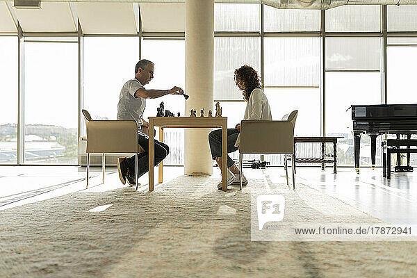 Mature businesswoman playing chess with young colleague in office