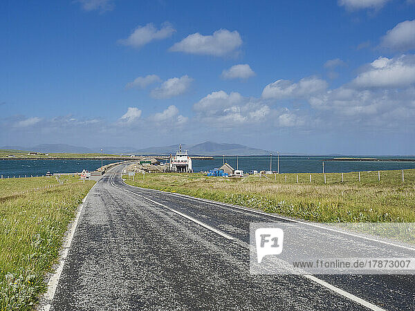 UK  Scotland  Empty asphalt road in Outer Hebrides with ferry in background