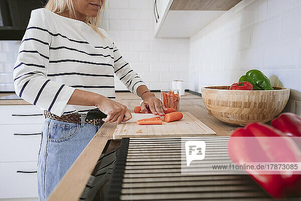 Woman cutting carrots in kitchen at home