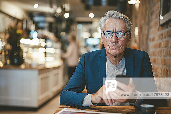 Businessman with mobile phone in cafe