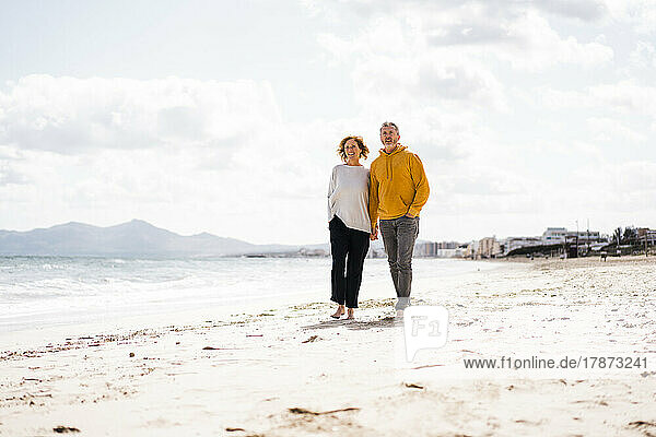 Älteres Paar spaziert am Strand entlang
