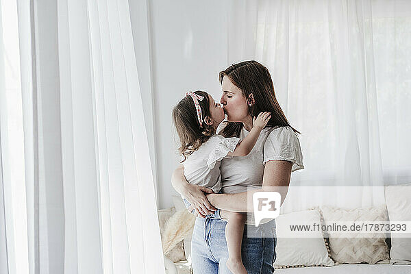 Mutter und Tochter küssen sich zu Hause
