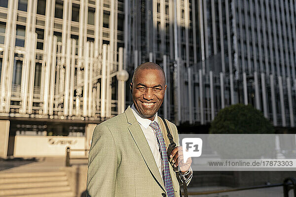Happy mature businessman in front of building at sunset