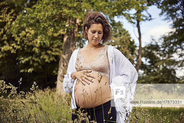Pregnant woman with hands on hip standing in grass