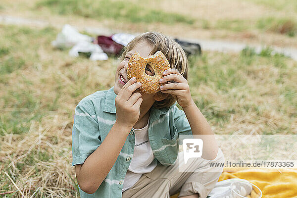 Boy looking through hole of bread