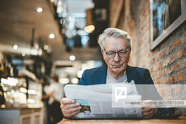 Businessman reading newspaper in cafe