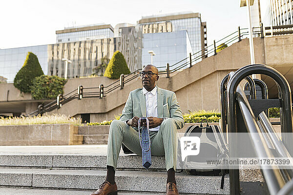 Mature businessman with necktie sitting on steps