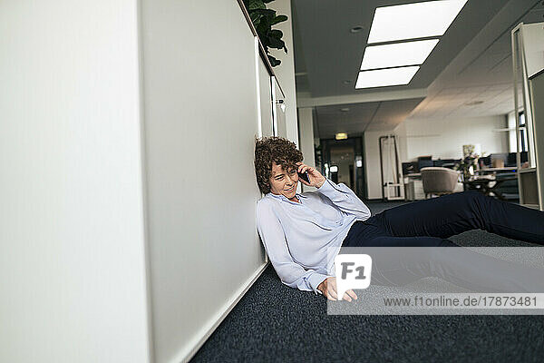 Smiling businesswoman talking on mobile phone reclining in office