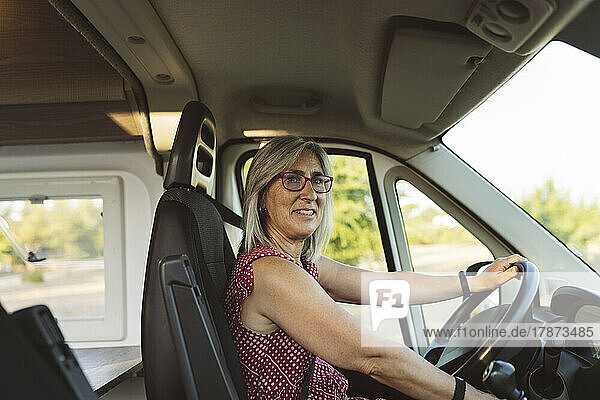 Mature woman driving camper van on road trip