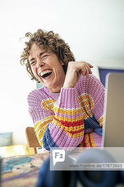 Mature woman with eyes closed laughing at home