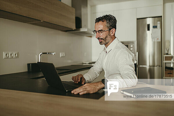 Businessman working on laptop at kitchen counter