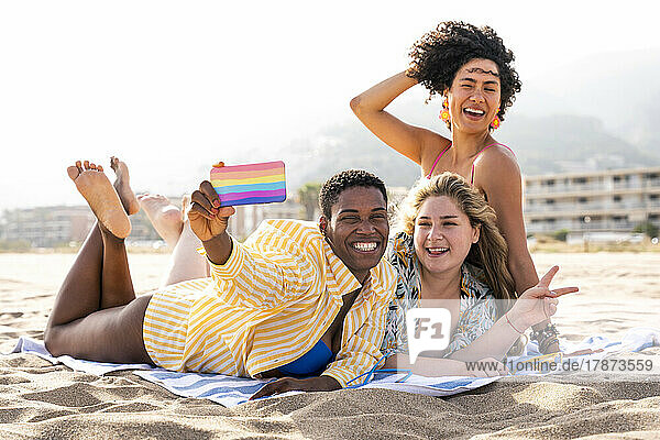 Happy multiracial friends taking selfie over mobile phone at beach