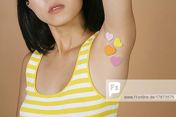 Woman with heart shape stickers on armpit