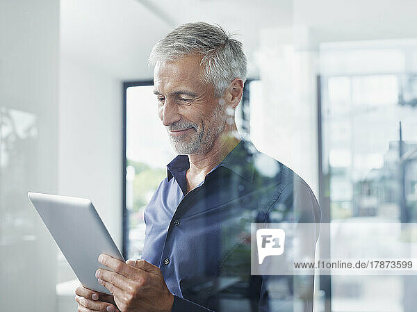 Smiling mature businessman using tablet PC in office