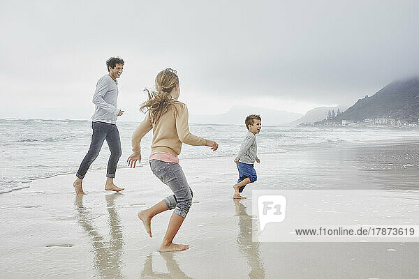 Father running on the beach with son and daughter