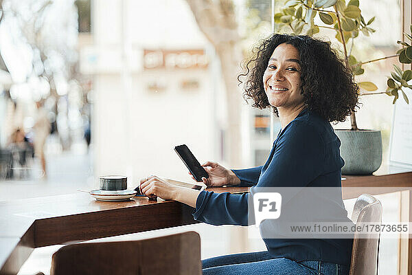 Happy woman with mobile phone in cafe