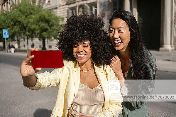 Happy multiracial friends taking selfie through smart phone