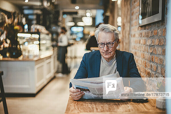 Senior businessman reading newspaper in cafe