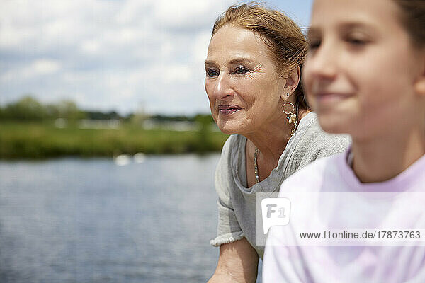 Smiling senior woman by granddaughter on sunny day
