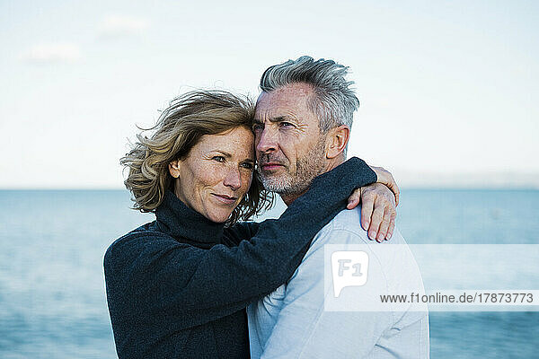 Smiling mature couple standing in front of sea