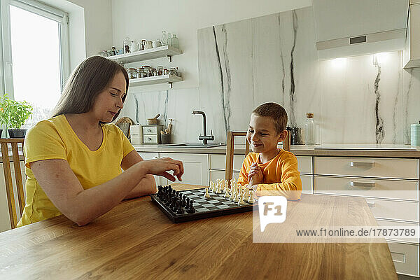 Mother and son playing chess in domestic kitchen