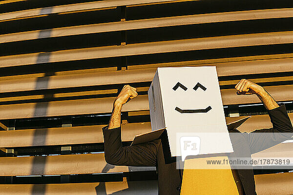 Man in triumphant pose wearing smiley face box