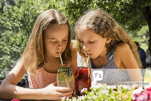 Mädchen mit Schwester trinkt Fruchtlimonaden