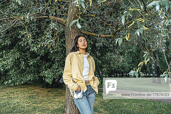 Woman relaxing standing in front of tree